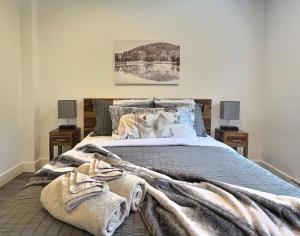 een slaapkamer met een bed met een deken en 2 lampen bij Condo sur 2 étages in Saint-Faustin