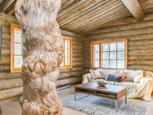 a living room with a table and a tree trunk at Holiday Home Kaasavuoren ranta by Interhome in Röölä