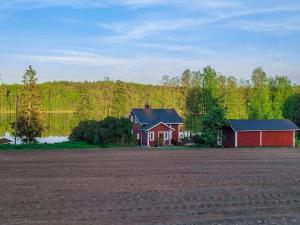 uma casa vermelha ao lado de um campo e um lago em Holiday Home Wanha karminranta by Interhome em Koirakivi