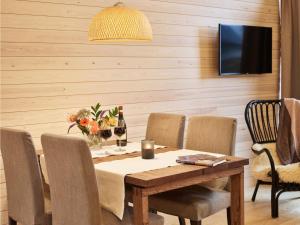 uma sala de jantar com uma mesa com cadeiras e uma televisão em Holiday Home Honka a by Interhome em Napapiiri