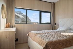a bedroom with a large bed and a large window at Fjordview Arctic Lodge with sauna and Jacuzzi in Lyngværet
