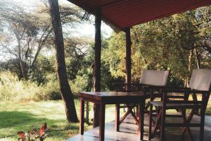 einen Tisch und Stühle unter einem Pavillon in der Unterkunft Drunken Elephant Mara in Sekenani