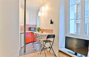 a kitchen with a table and a tv in a room at Appartement au coeur du Marais in Paris