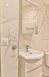 a white bathroom with a sink and a shower at Appartement au coeur du Marais in Paris