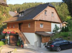 dom z drewnianym dachem i samochód zaparkowany przed budynkiem w obiekcie Müllnerhof w mieście Aich