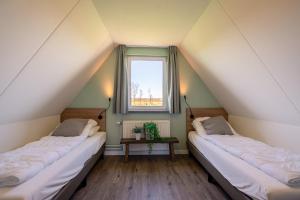 2 camas en un ático con ventana en Nieuwlanderweg 75, en De Waal
