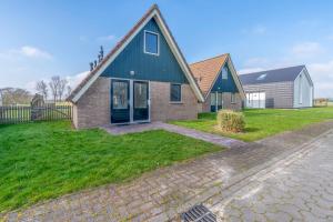 a brick house with a blue roof on a green yard at Nieuwlanderweg 75 in De Waal