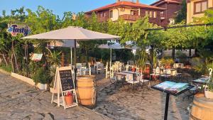 a patio with an umbrella and tables and chairs at Stankoff Hotel in Nesebar