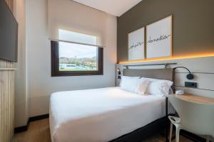 a bedroom with a bed and a desk and a window at Leonardo Hotel San Sebastián in Donostia-San Sebastián