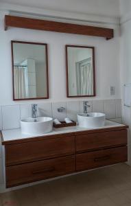 two sinks in a bathroom with two mirrors at Rainbow Inn in Grand Bras