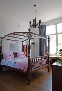 um quarto com uma cama de dossel com lençóis cor-de-rosa em B&B Het Oude Postkantoor em Yerseke