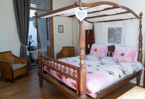 B&B Het Oude Postkantoor في يرسك: غرفة نوم مع سرير المظلة الخشبية مع الوسائد الزهرية