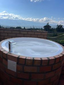 a hot tub in a brick wall with mountains in the background at MALOKAS AGUA VIDA & NATURALEZA in Villa de Leyva