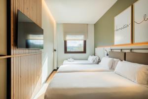 two beds in a room with two windows at Leonardo Hotel San Sebastián in Donostia-San Sebastián