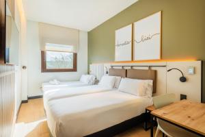 two beds in a room with a desk and a table at Leonardo Hotel San Sebastián in Donostia-San Sebastián
