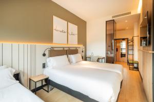 a hotel room with a large white bed and a bathroom at Leonardo Hotel San Sebastián in Donostia-San Sebastián