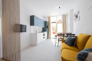 a living room with a yellow couch and a kitchen at FLORIT FLATS - Stylish Studio by the Joaquin Sorolla Station in Valencia +24 photos