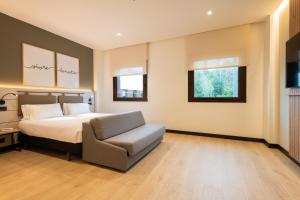a bedroom with a bed and a chair at Leonardo Hotel San Sebastián in Donostia-San Sebastián