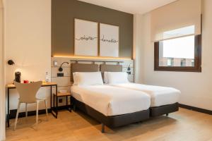 a bedroom with a bed and a desk and a desk at Leonardo Hotel San Sebastián in Donostia-San Sebastián