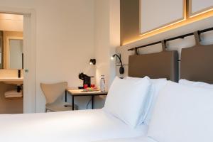 a bedroom with a bed and a table with a chair at Leonardo Hotel San Sebastián in Donostia-San Sebastián