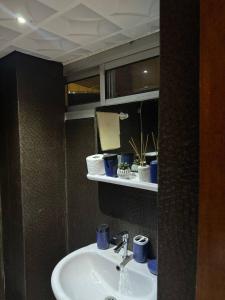 um lavatório de casa de banho com copos azuis numa prateleira em appartement cosy moon bonapriso em Douala