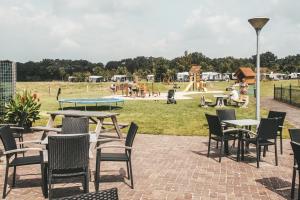 un patio con mesas y sillas y un parque infantil. en Camping Dal van de Mosbeek, en Mander