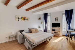 a bedroom with a bed and a table and a tv at Wood Mood - charmant studio central in Toulouse