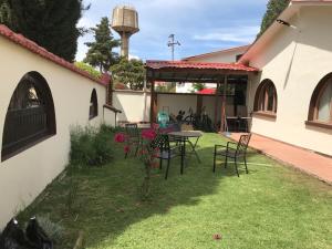 een tuin met stoelen en een tafel en een kerk bij La Casa de Los Pinos in Cochabamba
