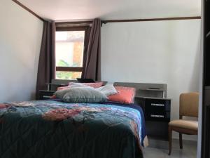 een slaapkamer met een bed, een raam en een stoel bij La Casa de Los Pinos in Cochabamba