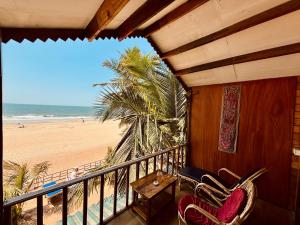 a balcony with two chairs and a view of the beach at Jardim a Mar in Agonda