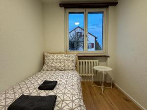 niewielka sypialnia z łóżkiem i oknem w obiekcie 4-Zimmerwohnung in Einfamilienhaus mit Garten und Parkplatz w mieście Volketswil