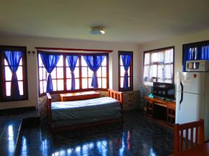 Schlafzimmer mit einem Bett, einem Kühlschrank und Fenstern in der Unterkunft Casa Las Violetas, Ushuaia in Ushuaia