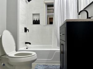 a white bathroom with a toilet and a bath tub at Harvrd-MIT-B.U./Parkfree/Single Family residence in Boston