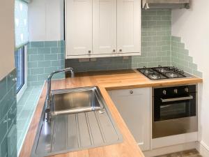 a kitchen with a sink and a stove at Cosy Cottage in Bourton on the Hill