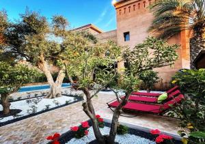 a red bench in a courtyard with trees and flowers at Villa Ghali de Luxe & Golf in Marrakesh