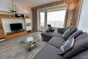 a living room with a gray couch and a television at Haus "Nautilus" Appartement NAU24 in Duhnen