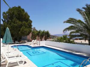 a swimming pool with white chairs and a swimming pool at PROFILIO Apartments & Studios in Exopoli