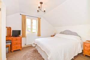 ein weißes Schlafzimmer mit einem Bett und einem TV in der Unterkunft The Hayloft in Newchurch