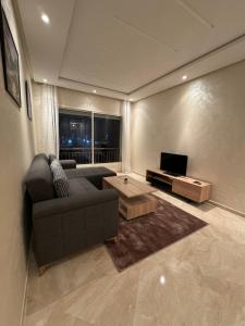 Una sala de estar con un sofá y un televisor. en Bouznika Beach appartement de luxe avec piscine, en Bouznika