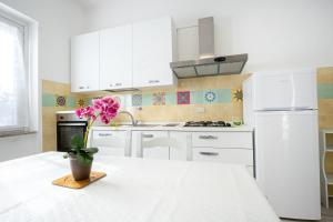 een keuken met witte kasten en een vaas met een bloem op een tafel bij Appartamento Libeccio a 300m dalla spiaggia in Golfo Aranci
