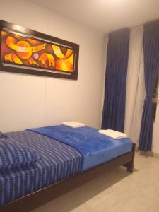 a bedroom with a bed and a painting on the wall at APARTAMENTO AMOBLADO SECTOR MARAYA in Pereira