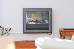 einen Kamin im Wohnzimmer mit einem TV in der Unterkunft The Wing at Fox Hollow in Ventnor