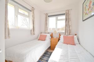 two beds in a room with two windows at Lobster Pot, 66 Salterns Beach Bungalows, Seaview in Seaview
