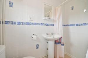 a white bathroom with a sink and a toilet at Lobster Pot, 66 Salterns Beach Bungalows, Seaview in Seaview