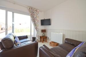 a living room with two leather couches and a tv at Lobster Pot, 66 Salterns Beach Bungalows, Seaview in Seaview