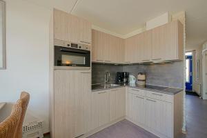 a large kitchen with wooden cabinets and a sink at Appartement Seinpost 26 - Callantsoog in Callantsoog