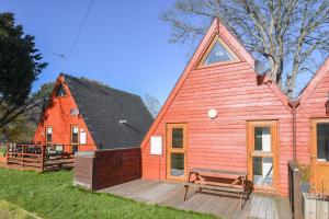 a red house with a bench on a deck at Chalet Two in Deal
