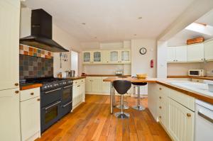 a kitchen with white cabinets and a wooden floor at Red House in Seaview