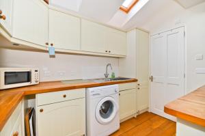 a kitchen with white cabinets and a washer and dryer at Red House in Seaview