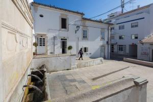 a person walking down a street in front of buildings at Bicas Velhas Studio in Loulé